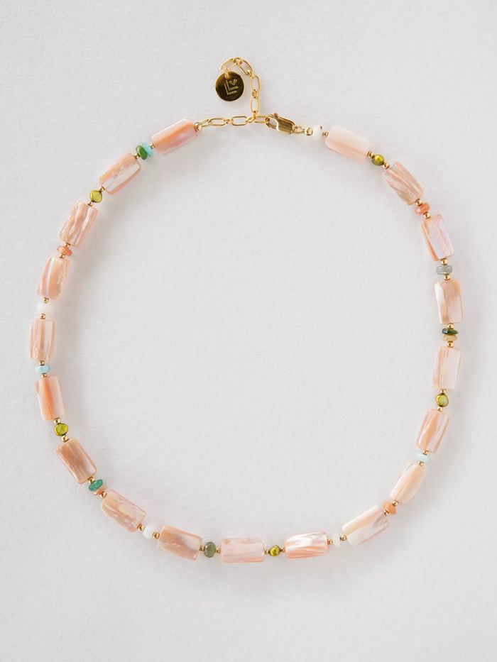 Necklace with pink beads and gold clasp on a light gray background