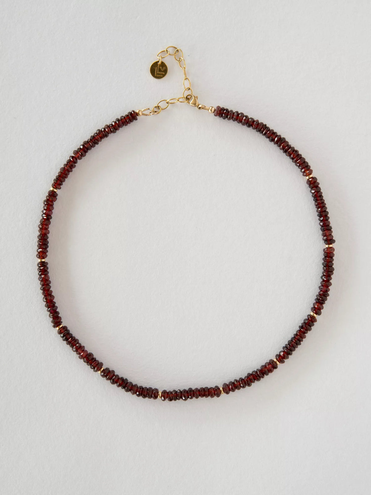 Necklace with garnet and gold beads on a light gray background