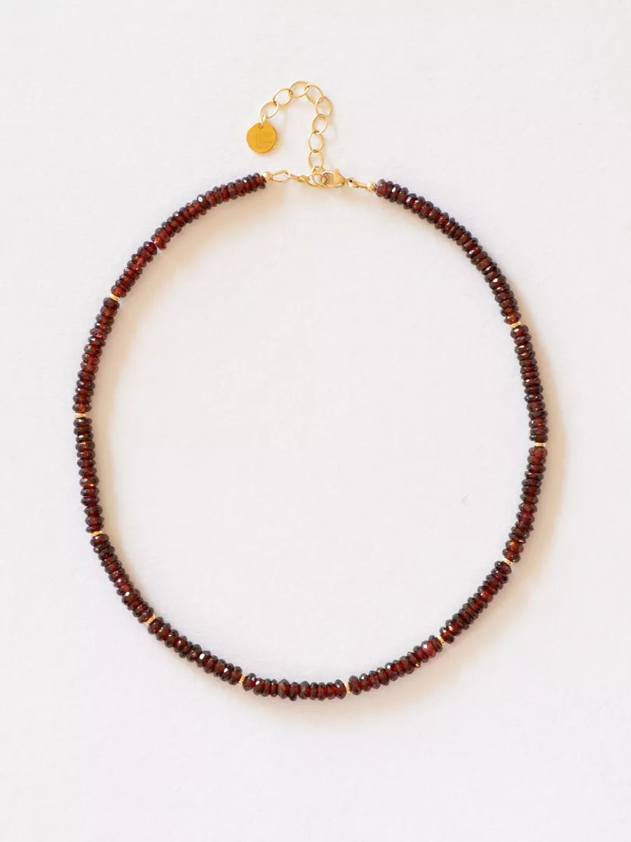 Garnet necklace with solid gold beads and clasp on a white background.
