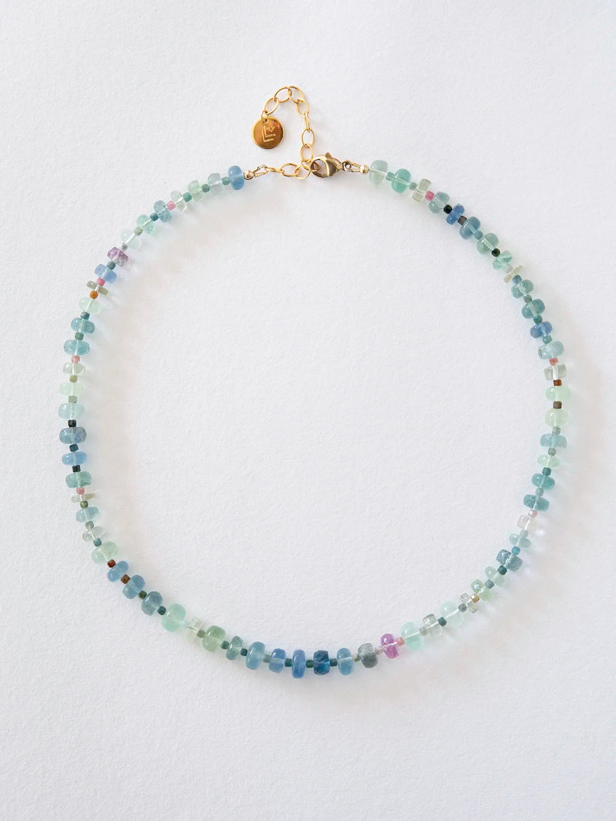 A beaded necklace made of small faceted beads in shades of light blue, mint green, and turquoise, with a gold-filled clasp and chain, displayed on a clean white background.