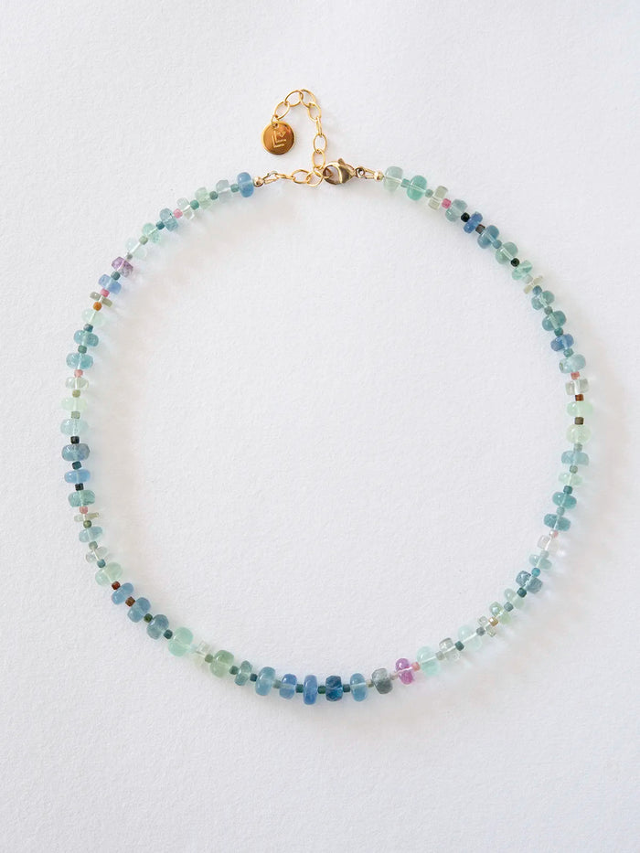 A beaded necklace made of small faceted beads in shades of light blue, mint green, and turquoise, with a gold-filled clasp and chain, displayed on a clean white background.