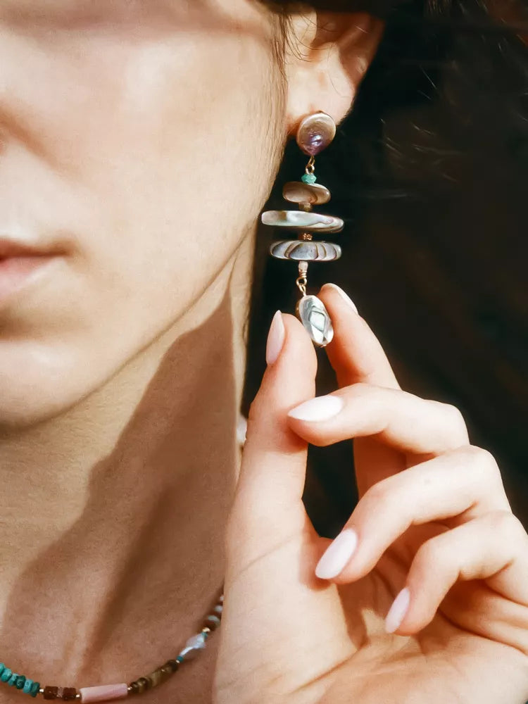 Close-up of a person wearing a drop earring with a blurred background